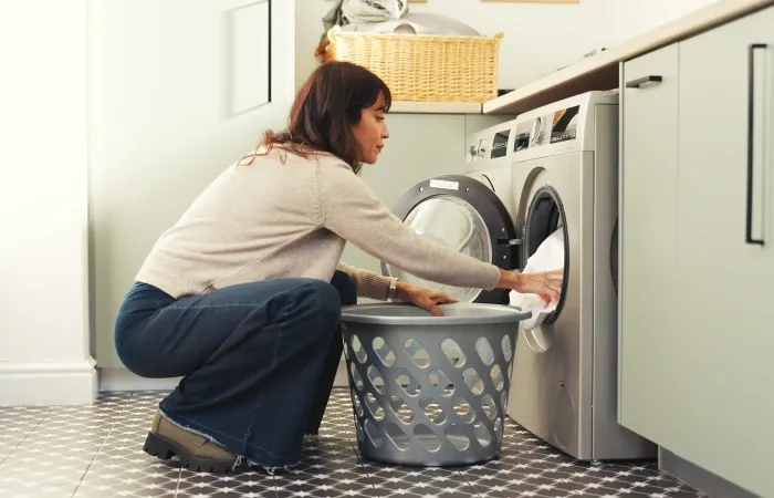 Imagem de uma mulher colocando roupas em uma lava e seca