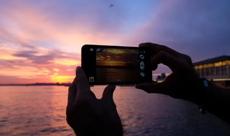 Pessoa tirando foto de paisagem em pôr do sol 