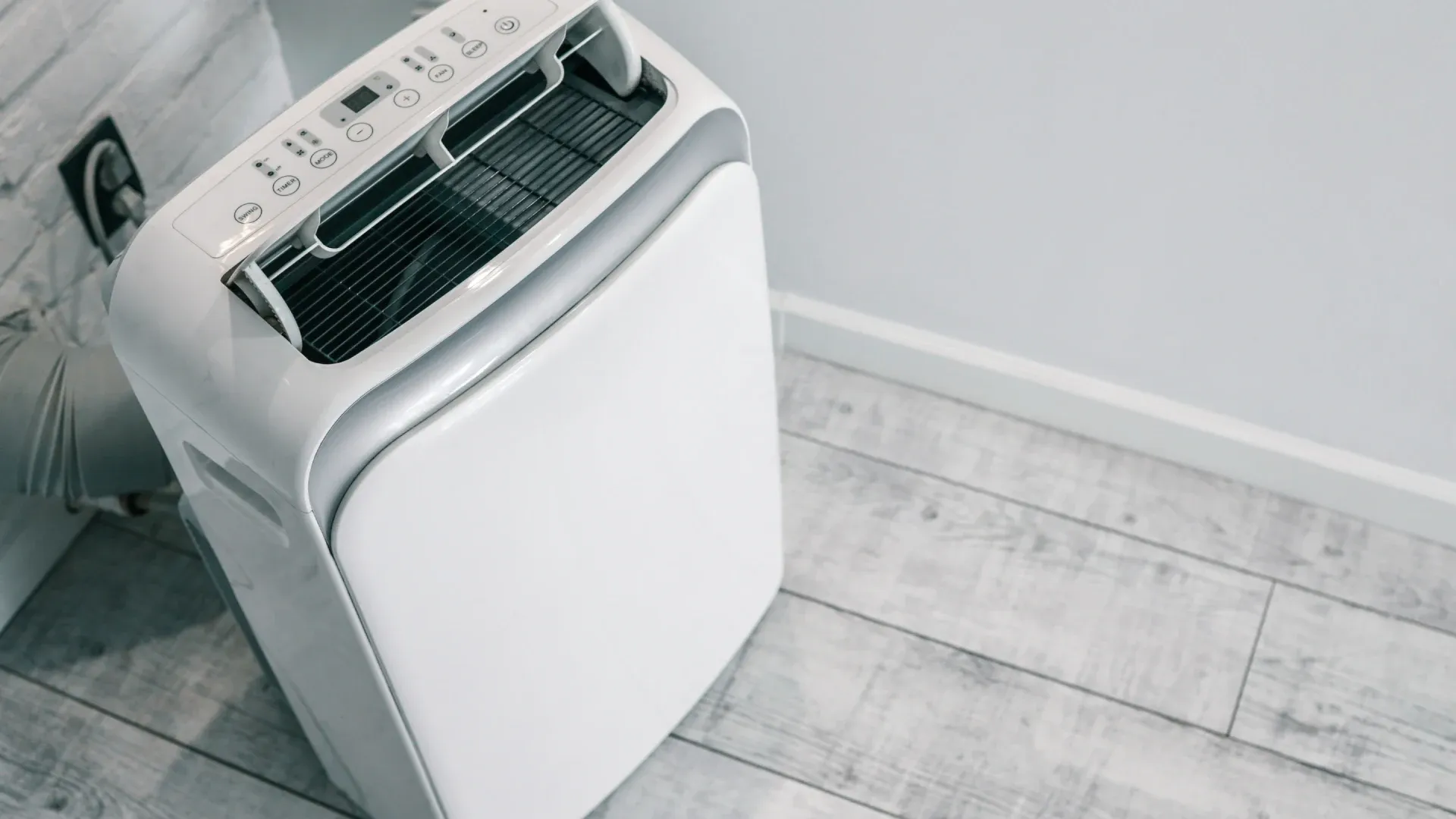 ar-condicionado móvel com visor digital e painel de controle próximo a uma tomada elétrica.