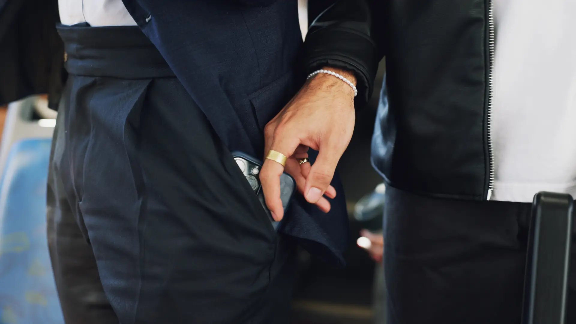 Mão furtando um celular do bolso de outro homem