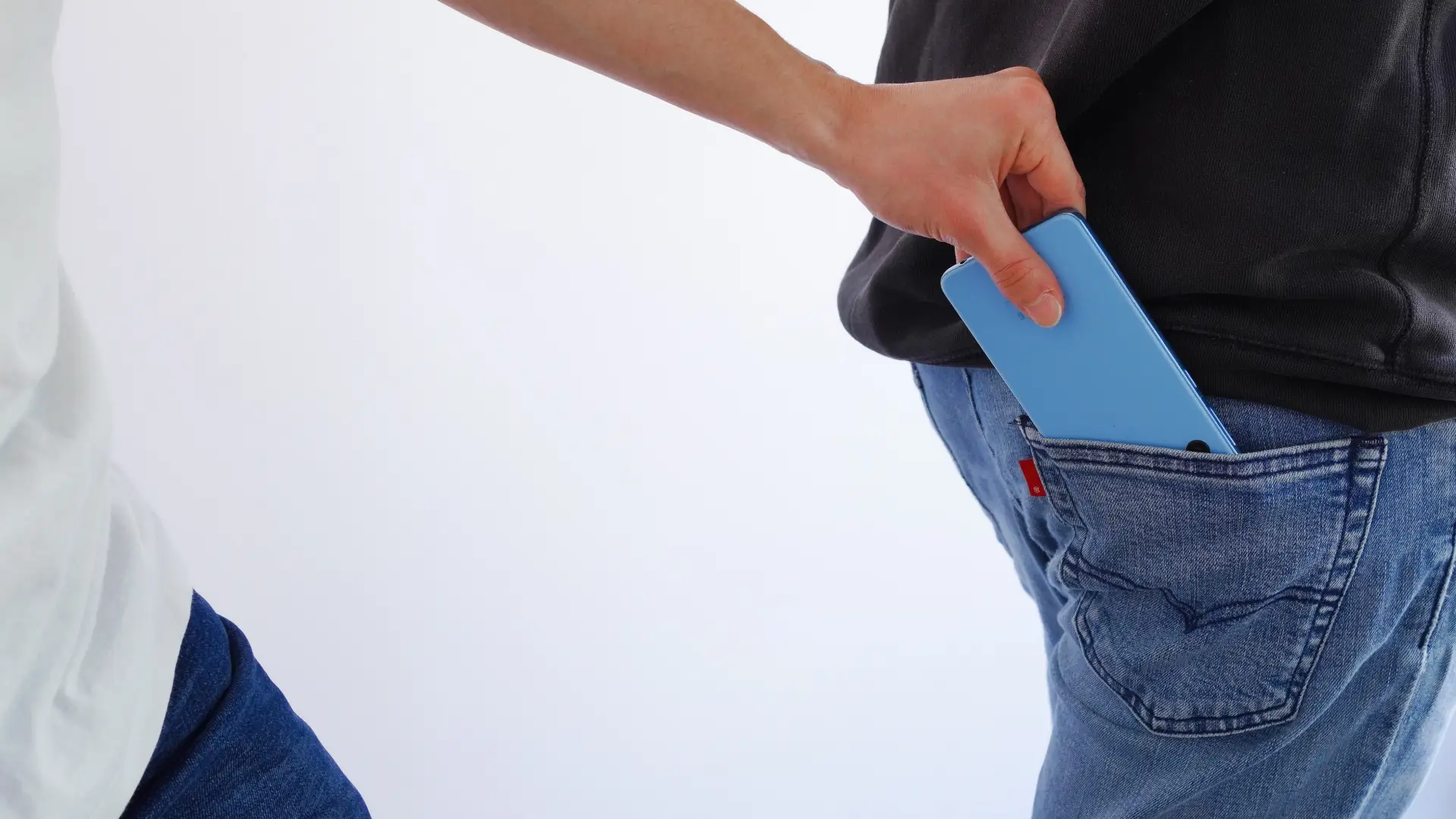 Uma pessoa segura o celular perto da calça de outra pessoa