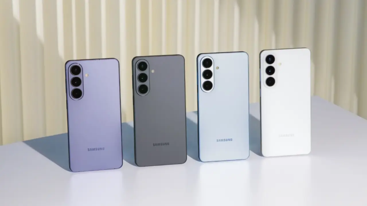 Quatro smartphones Galaxy S26 vistos de trás, em pé, nas cores roxo, cinza, azul claro e branco, com câmeras alinhadas verticalmente