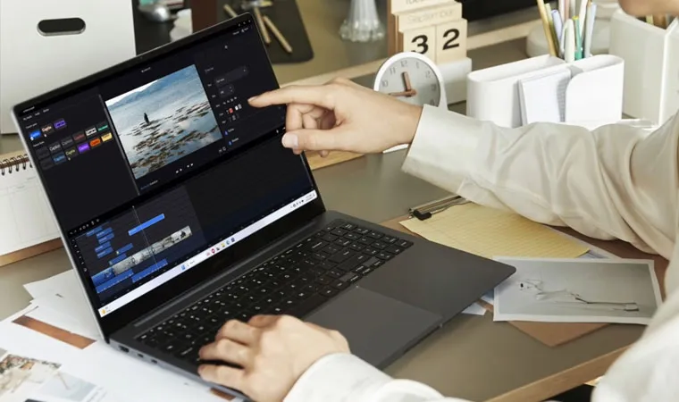 Foto de uma pessoa usando um Notebook Samsung Galaxy Book4 aberto sobre uma mesa apontando para a tela enquanto edita um vídeo