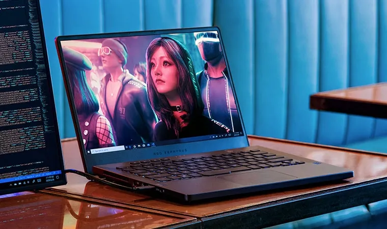 Foto de um ASUS ROG Zephyrus sobre a mesa exibindo uma arte cyberpunk com uma jovem olhando para o alto e outros personagens ao fundo