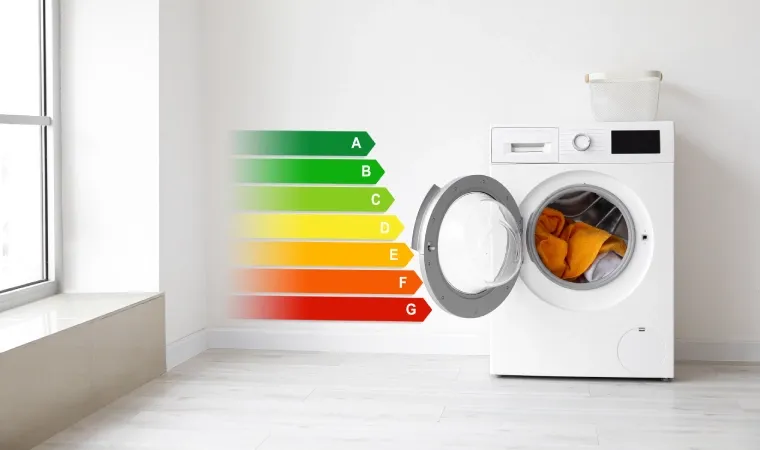 Máquina de lavar branca com roupas no tambor. Ao lado, a tabela de eficiência energética projetada numa parede branca. 