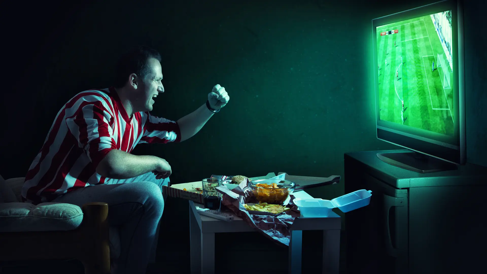 Imagem de um homem torcendo enquanto assiste um jogo de futebol na TV