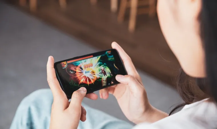 Uma pessoa segura um celular na horizontal enquanto na tela aparece um jogo