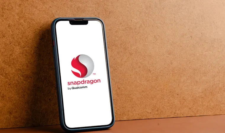 Imagem mostra um celular encostado em uma parede. Na tela aparece a palavra Snapdragon