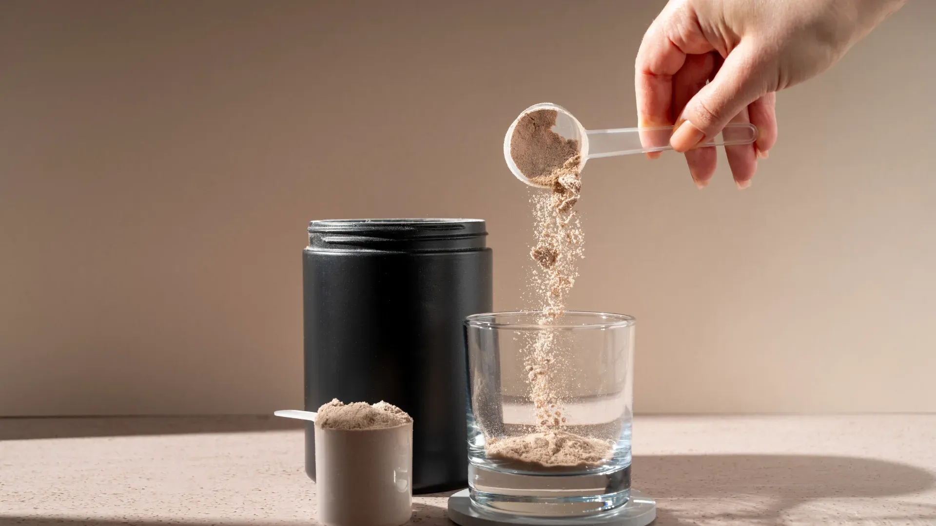 Imagem de uma pessoa retirando whey protein de um scoop e colocando em um copo.