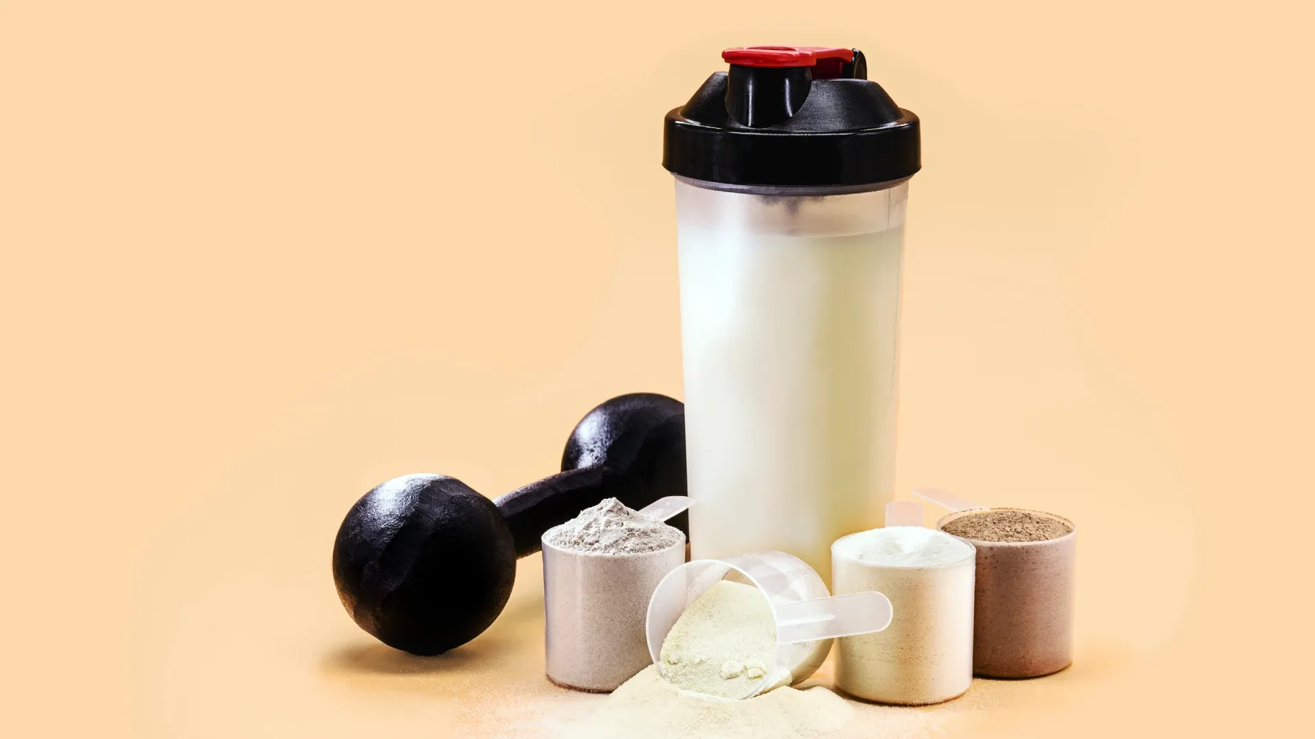 Imagem de vários scoops de whey, além de um shaker de whey com o produto.