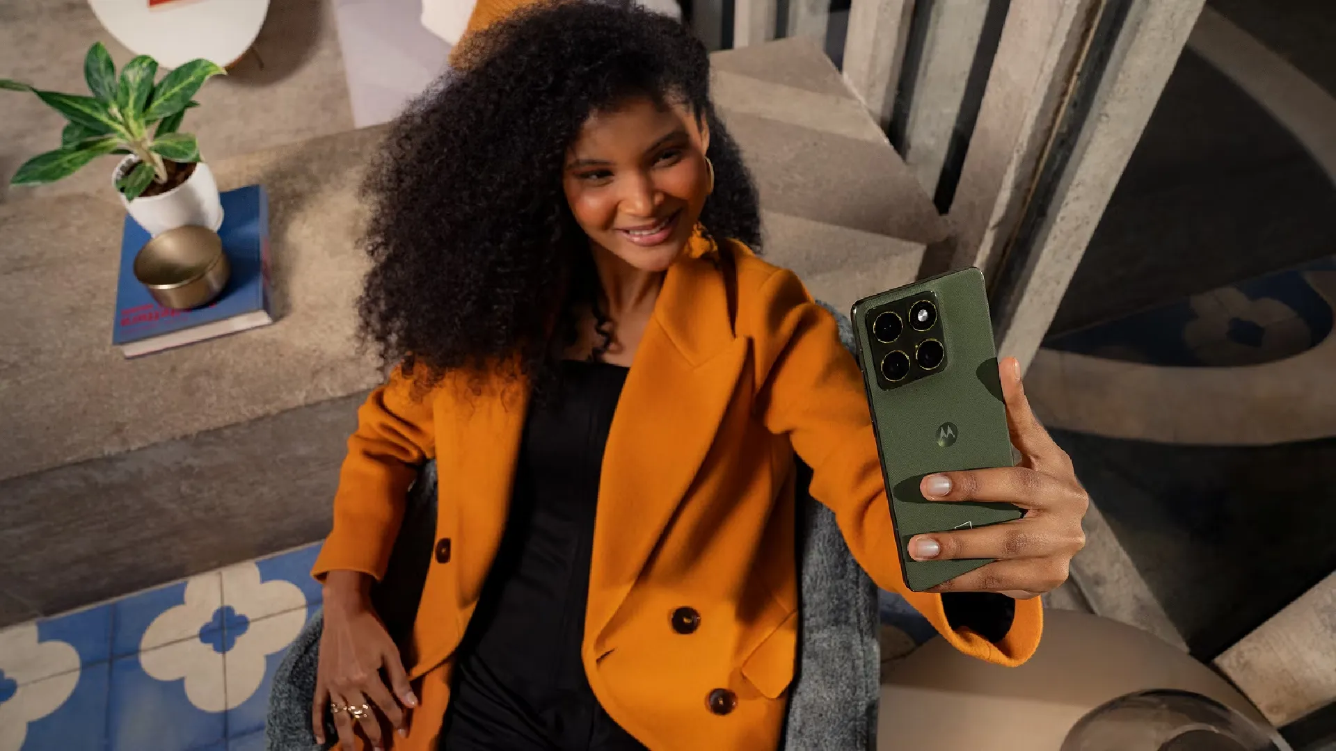 Mulher tirando selfie com o Motorola Edge 70 na cor verde, mostrando o módulo traseiro com três câmeras de 50MP