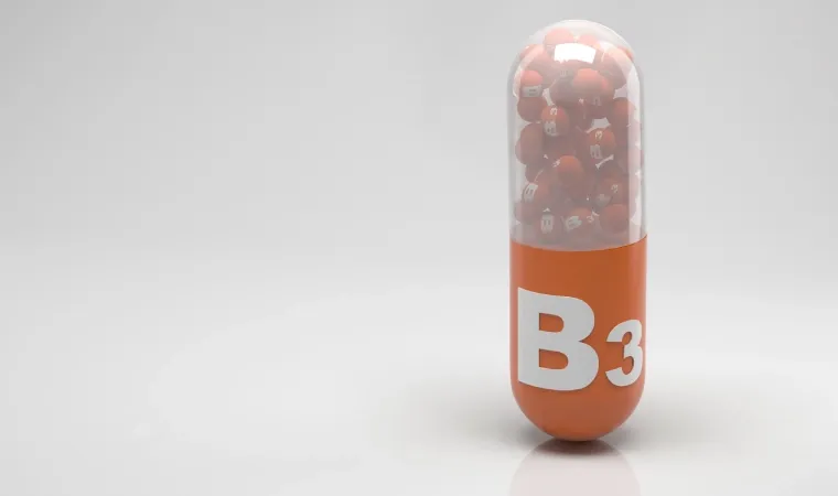 Cápsula laranja de vitamina B3 e fundo branco