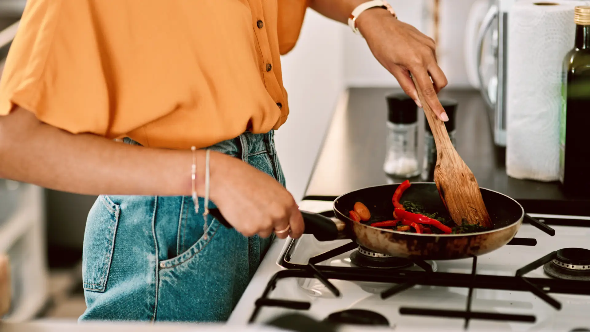 Mulher cozinhando em frigideira no fogão da cozinha