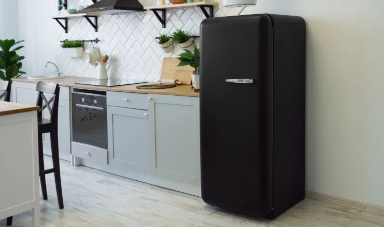 Imagem de uma geladeira preta em meio a uma cozinha