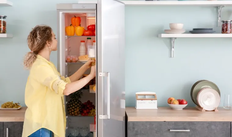  mulher pegando itens dentro de uma geladeira 