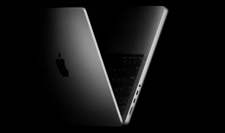 Montagem mostra o Notebook Apple Macbook Pro M5 com a tampa entreaberta em primeiro plano com fundo escuro