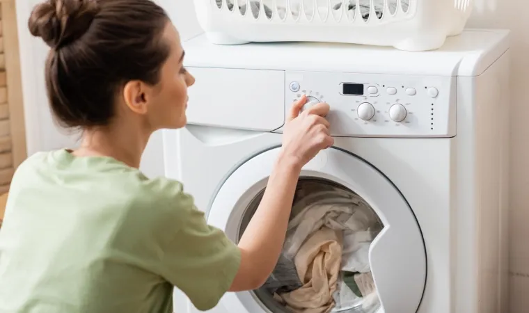mulher selecionando um ciclo de lavagem em sua máquina de lavar roupa