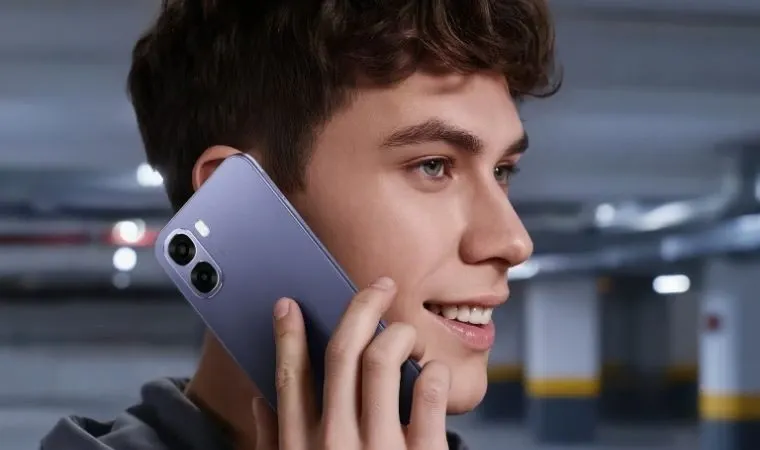 Homem jovem de olhos verdes em uma garagem usa o Celular Oppo A6x em ligação telefônica.