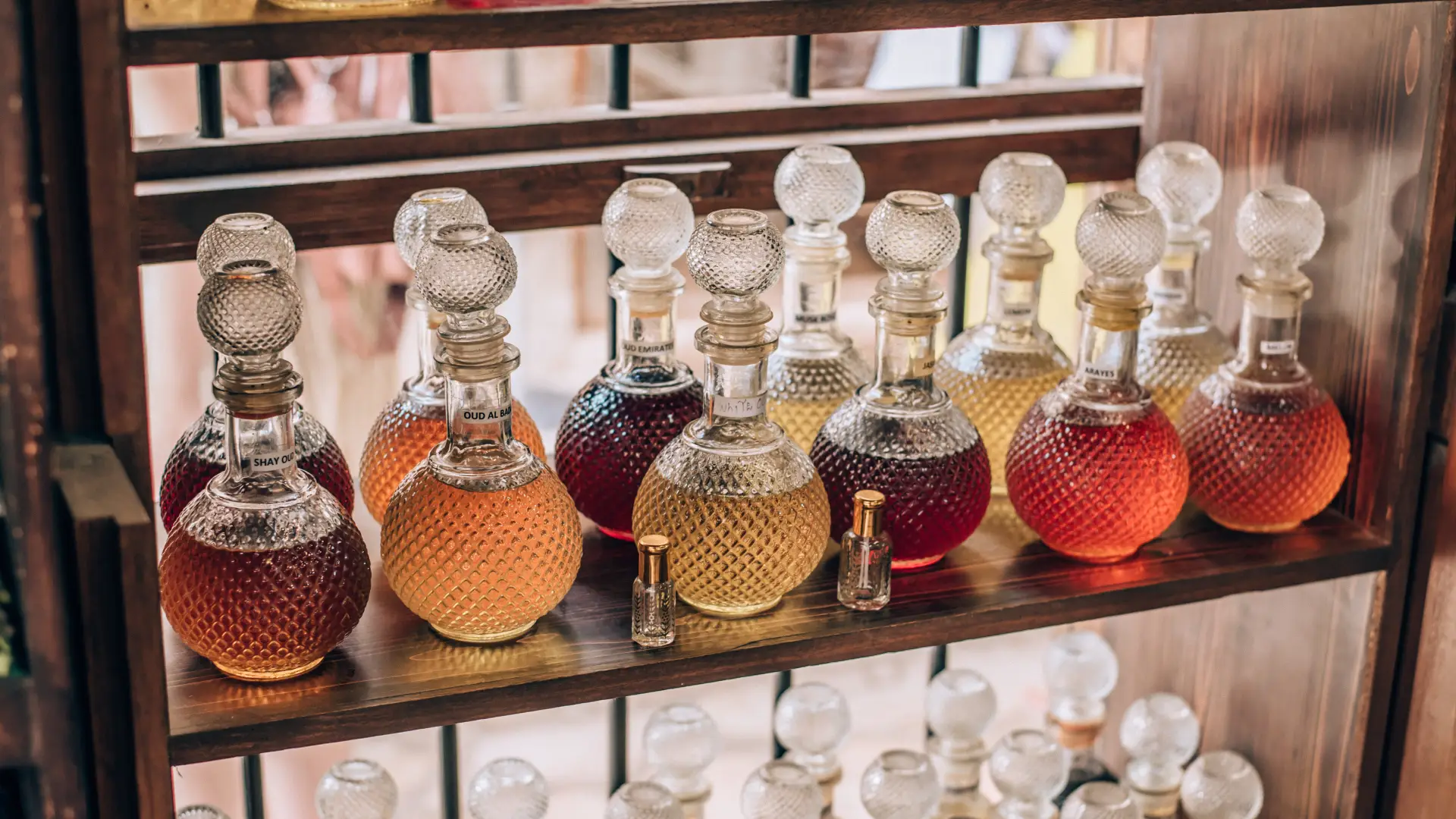 Imagem de uma prateleira com vários frascos de perfumes árabes femininos