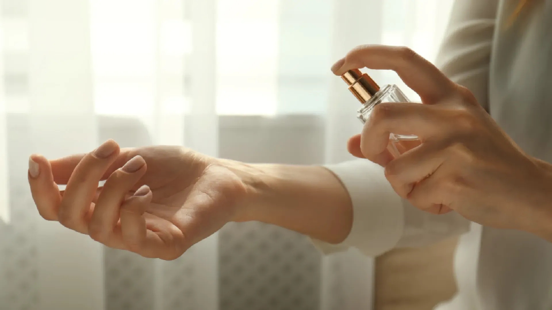 Close em mão feminina aplicando perfume no próprio pulso