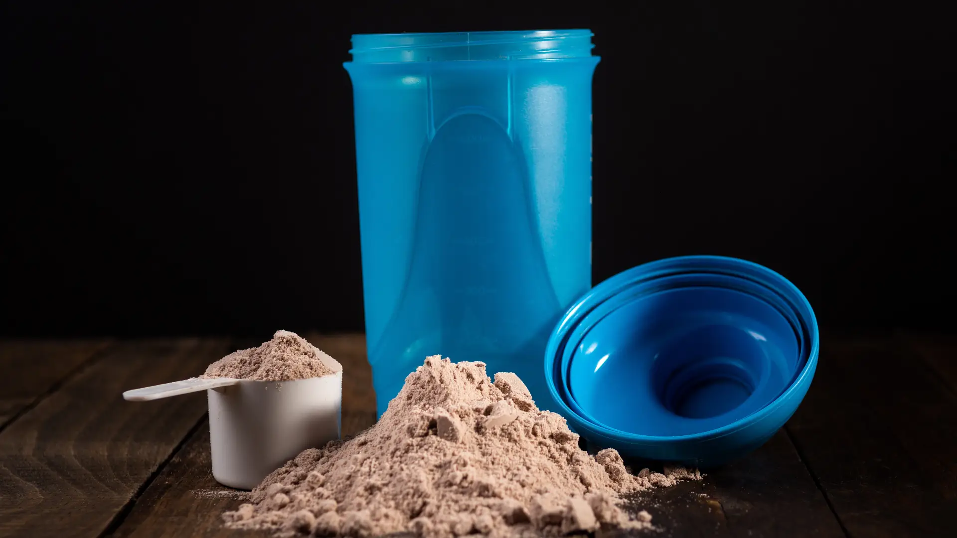 Whey protein chocolate ao lado do scoop e da shakeira