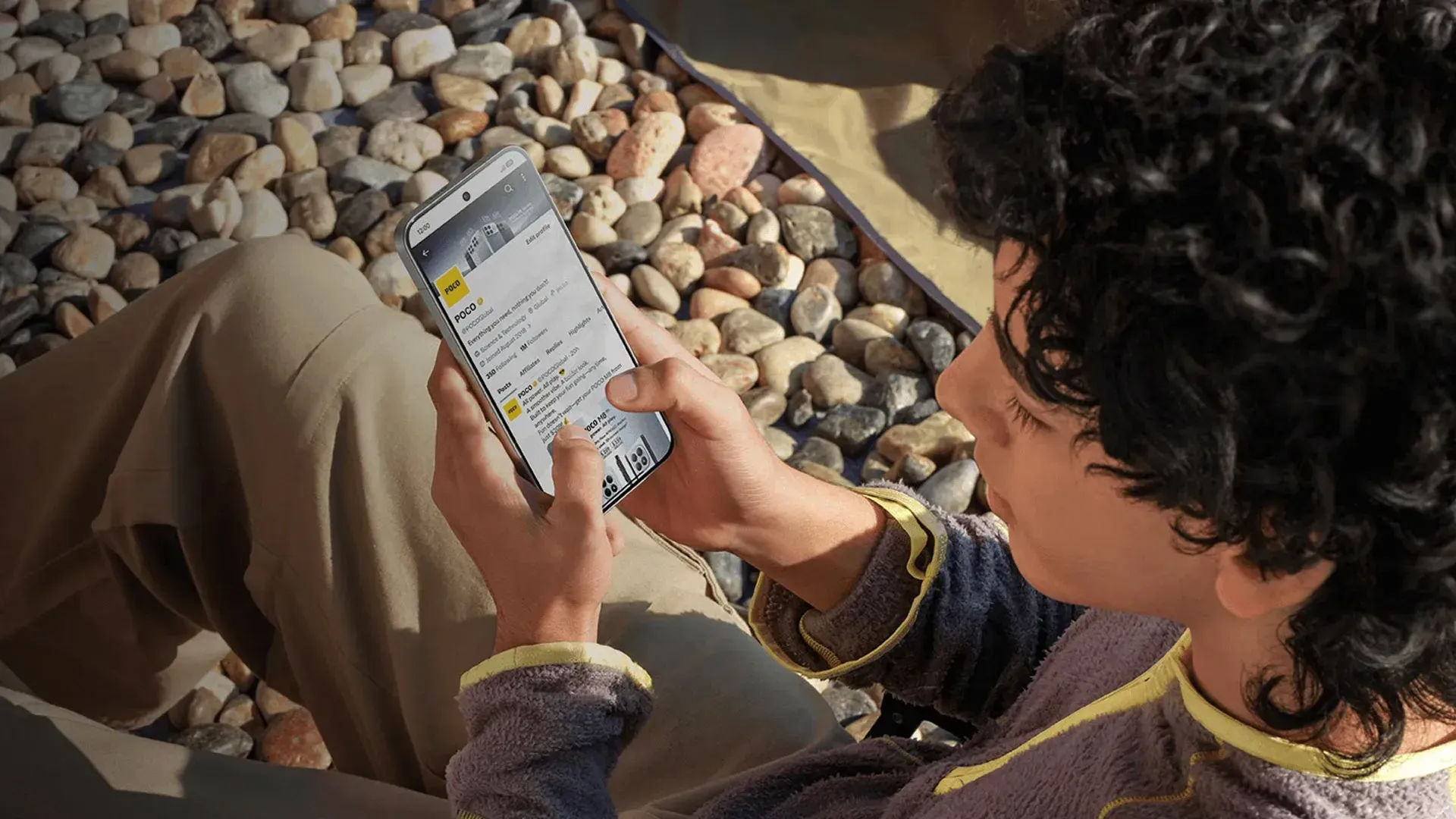 Imagem de uma pessoa segurando o POCO X8 Pro Max e usando a tela sob luz solar direta