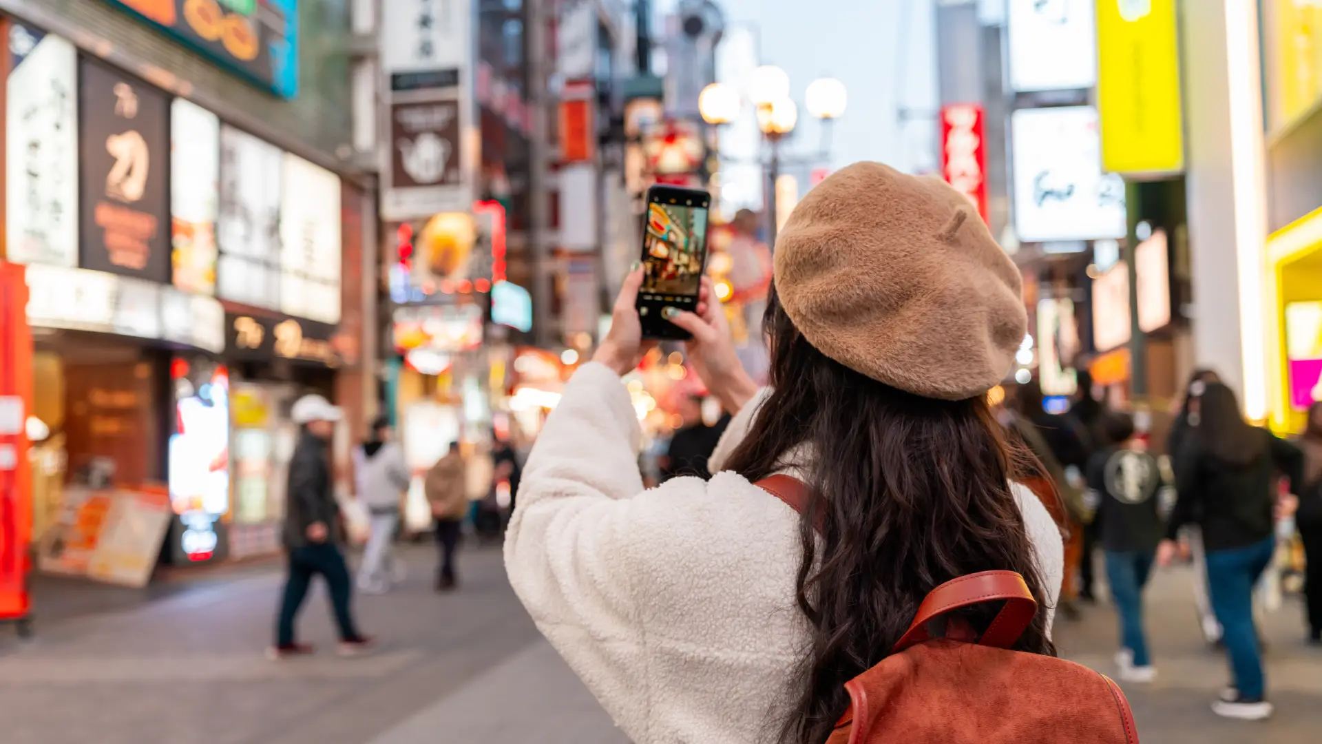 Uma mulher tira foto em uma rua movimentada