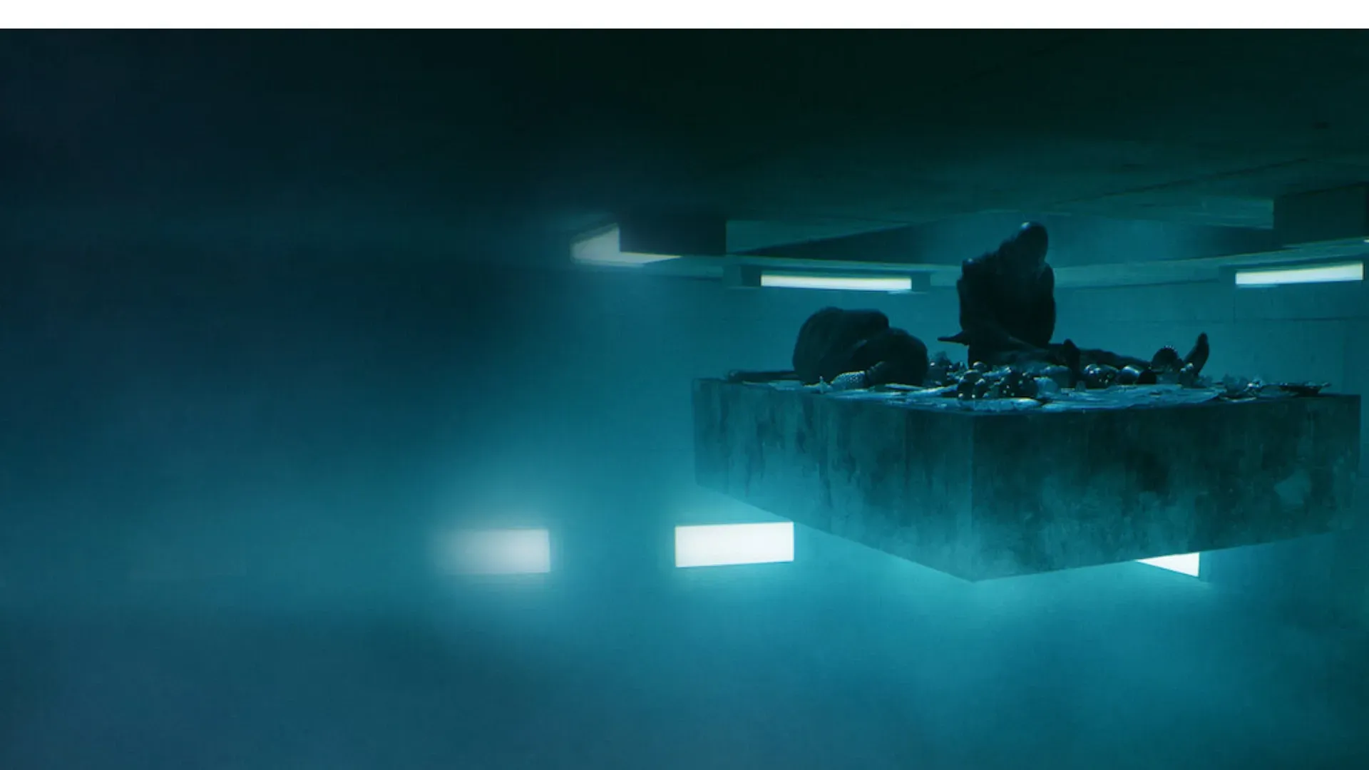 Plataforma flutuante com duas pessoas ajoelhadas sobre ela e com restos de comida em um ambiente escuro