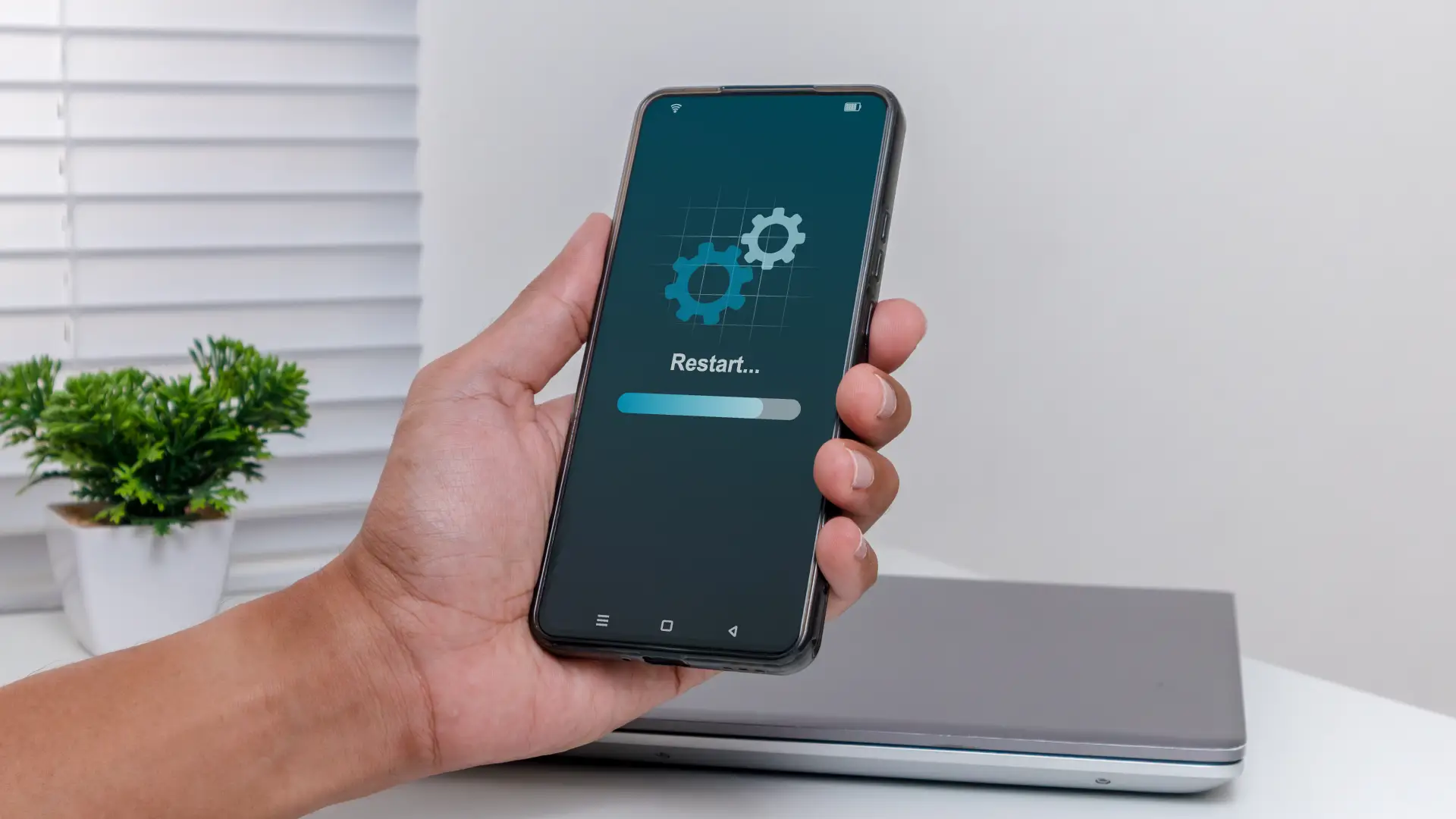 Homem segurando smartphone com sistema sendo reiniciado, simbolizando reinicialização e formatação do aparelho 