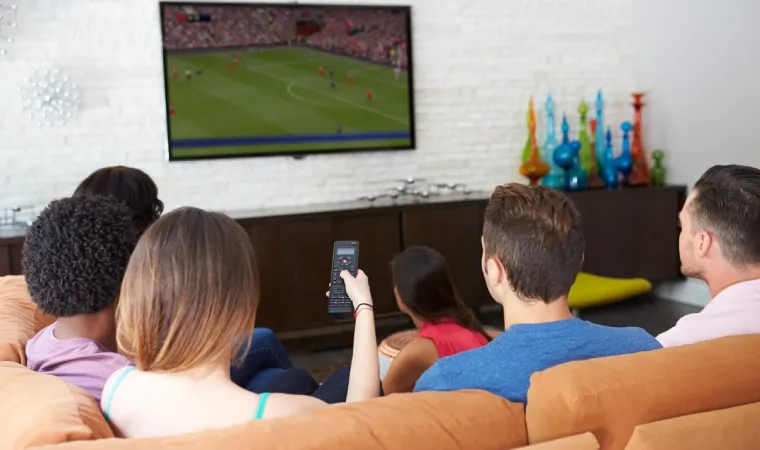 Amigos sentados no sofá assistindo um jogo da Copa do Mundo na TV da sala de estar