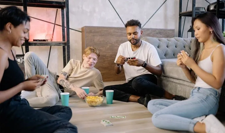 4 jovens adultos jogando UNO sentados no chão de uma sala