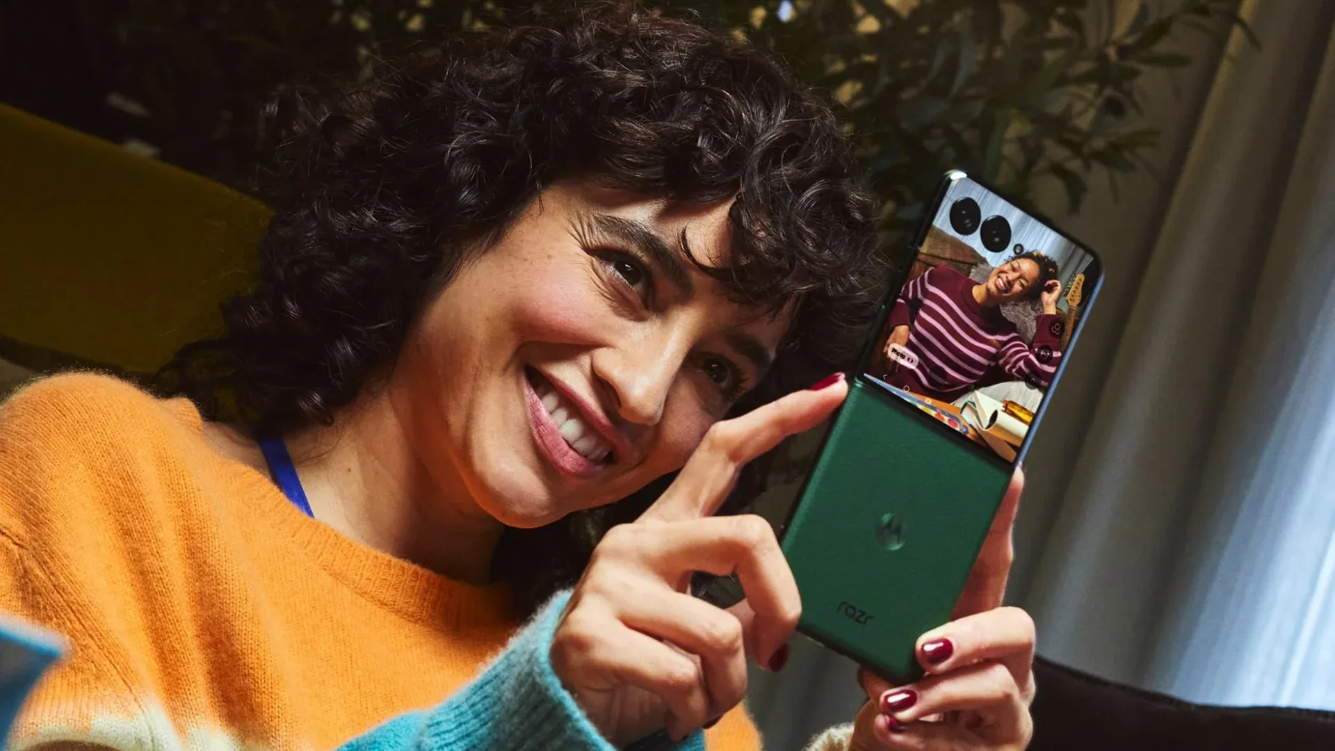 Imagem do Motorola Razr 70 Plus aberto mostrando a tela interna com vídeo e acabamento verde em couro vegano