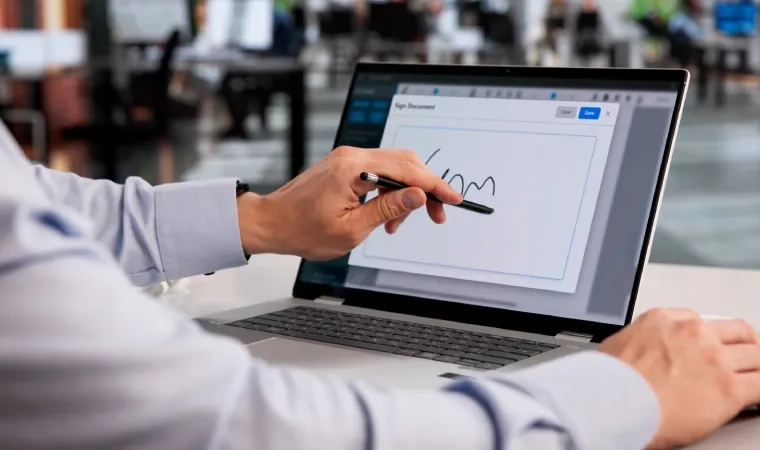 Imagem de uma pessoa escrevendo na tela de um notebook 2 em 1 usando uma caneta touch