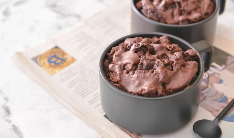 Duas xícaras pretas com bolo de caneca de chocolate com cobertura