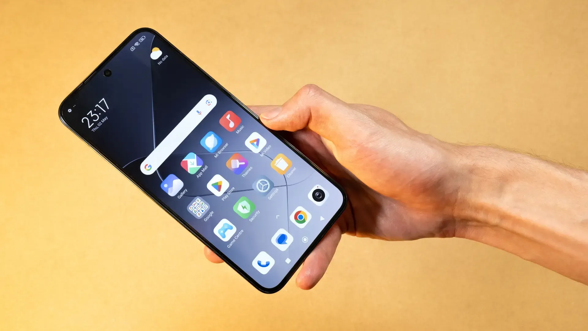 Mão segura smartphone Xiaomi com tela inicial aberta sobre fundo amarelo.